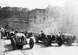 A classic F1 car driving through the streets of Monaco during a race.